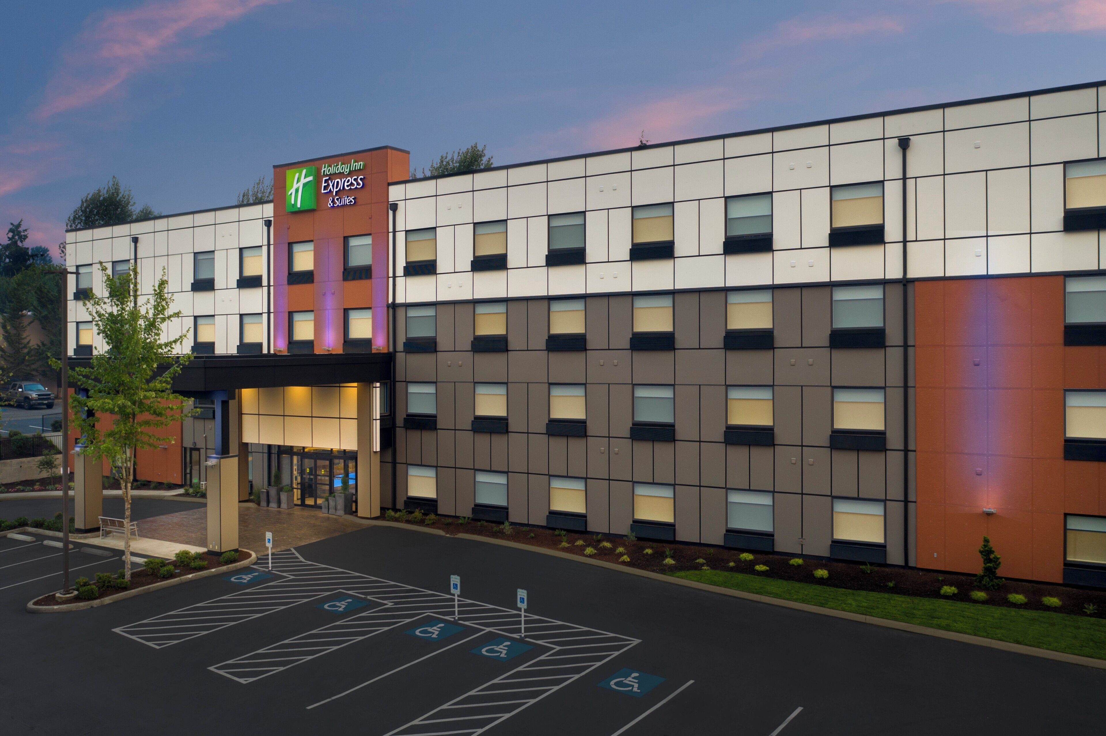 A Holiday Inn Express hotel with a modern facade, multiple parking spaces, and a landscaped entrance area.