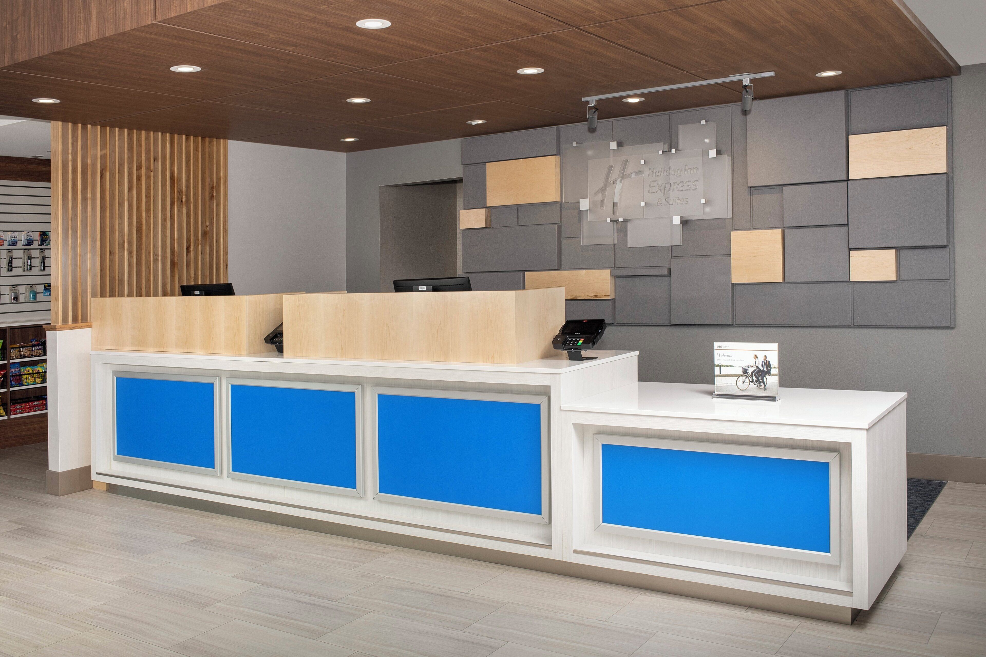 Un mostrador de recepción de diseño moderno, con una combinación de madera y paneles grises, y un panel azul de acento.