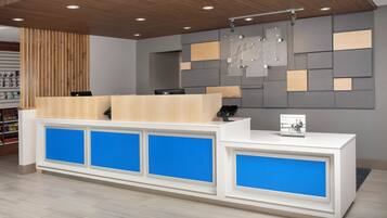 Un mostrador de recepción de diseño moderno, con una combinación de madera y paneles grises, y un panel azul de acento.