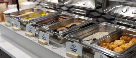 A buffet with labeled trays of food including turkey, sausage, gravy, and biscuits.