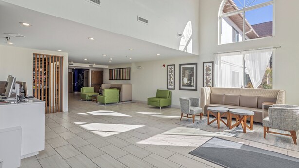A spacious lobby with a reception desk, green seating area, and a large window providing natural light. - Holiday Inn Express Hotel & Suites Torrington by IHG (Torrington)