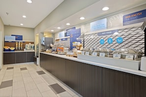 Un buffet de petit-déjeuner proposant une variété d'aliments, notamment une sélection de produits de boulangerie et un espace dédié aux plats chauds.