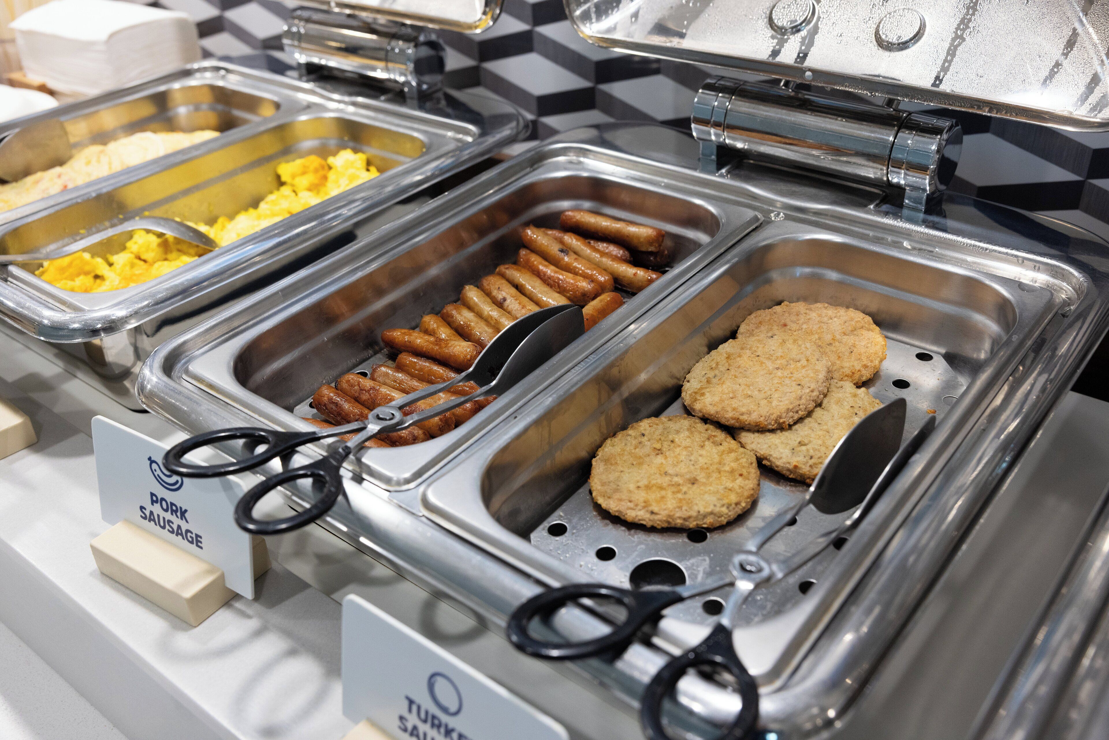A buffet with labeled containers for pork sausage, turkey sausage, and other items.