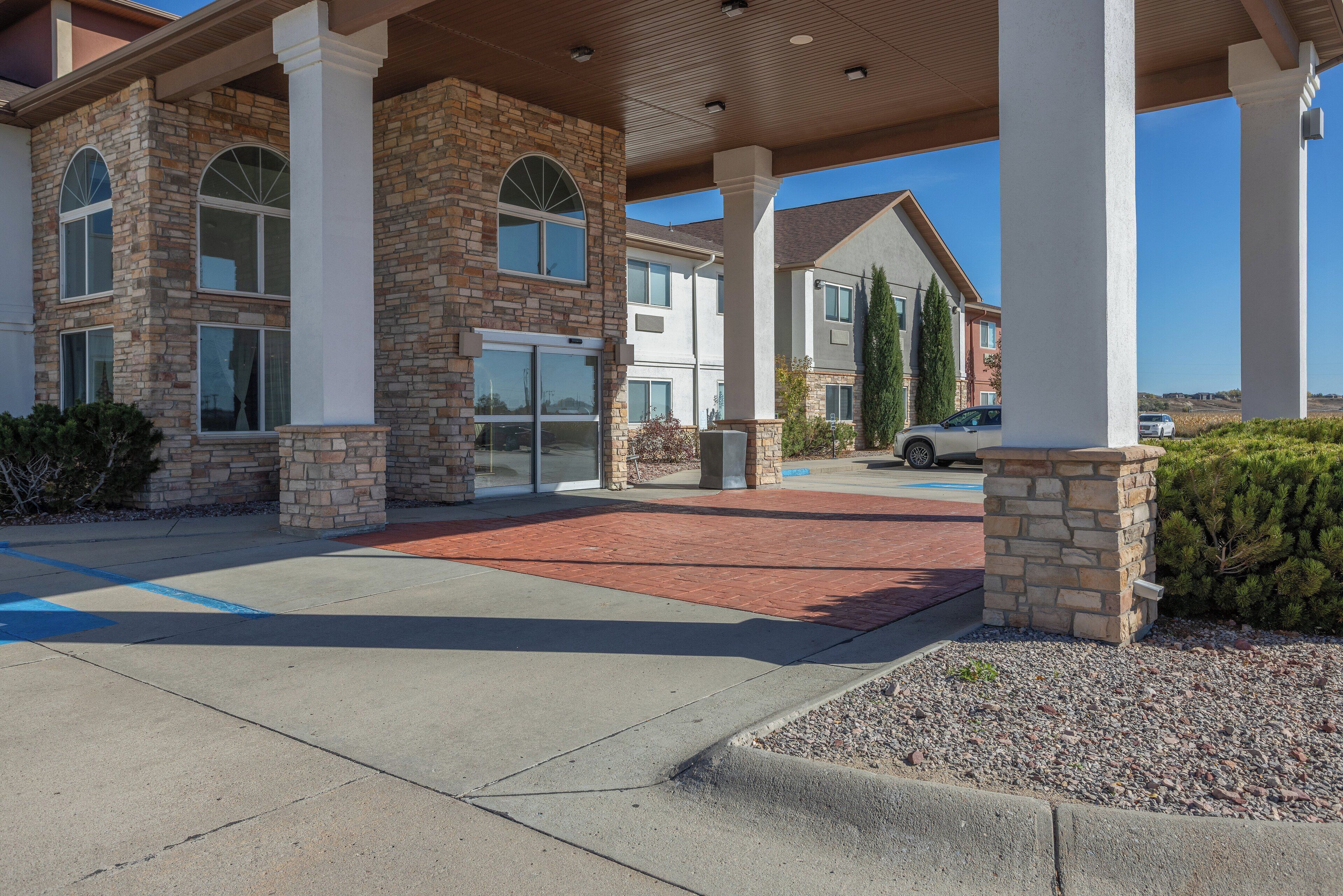 A hotel entrance with stone facade, large columns, and a covered walkway.