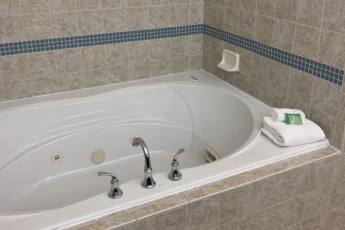 Un baño moderno con una bañera independiente, un cabezal de ducha manual y un inodoro empotrado.