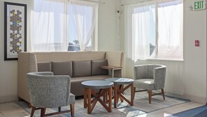 A modern lounge area with a sofa, two armchairs, and a small table. - Holiday Inn Express Hotel & Suites Torrington by IHG (Torrington)