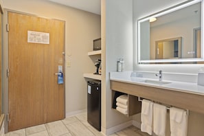 Une salle de bain avec une porte en bois, un lavabo avec un miroir et des serviettes suspendues à un porte-serviettes.