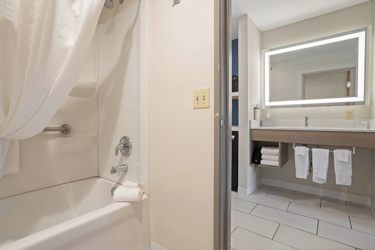 A modern bathroom with a bathtub, a vanity with a mirror, and a towel rack.