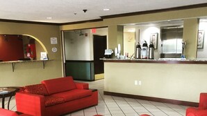 Un hall d’entrée avec des canapés rouges et un comptoir où sont disponibles divers services et commodités.