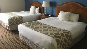 Deux lits doubles avec des couvre-lits à motifs, une table de chevet avec une lampe et un mur bleu.