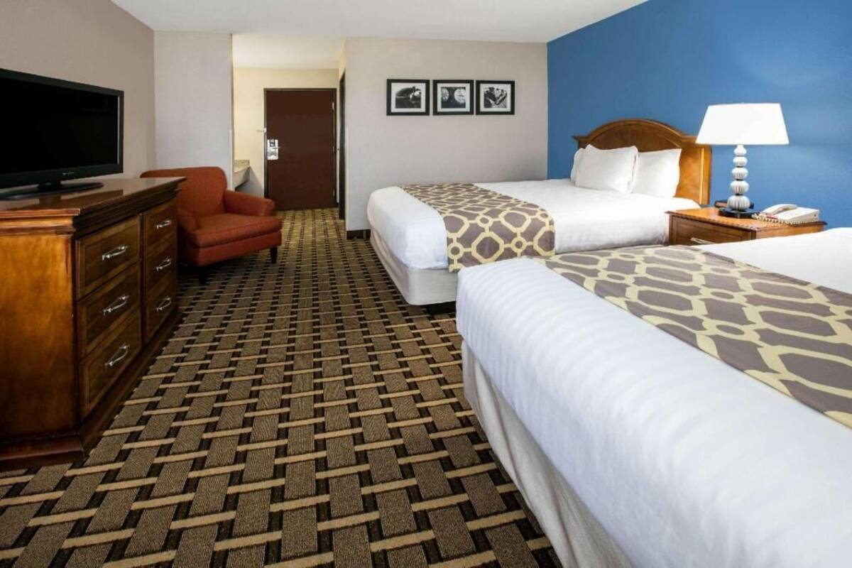 A hotel room with two beds, a TV, a desk, and a chair.