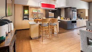 Eine moderne Küche mit Essbereich, Holzkohle-Stühlen, einer Kaffeemaschine und einem Kühlschrank.