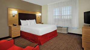 Ein Hotelzimmer mit einem großen Bett, einem Fernseher, einem Schreibtisch und einem Stuhl.