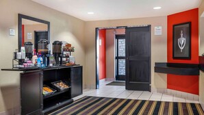 A hotel lobby with a coffee station, a reception desk, and a door leading to the business area.