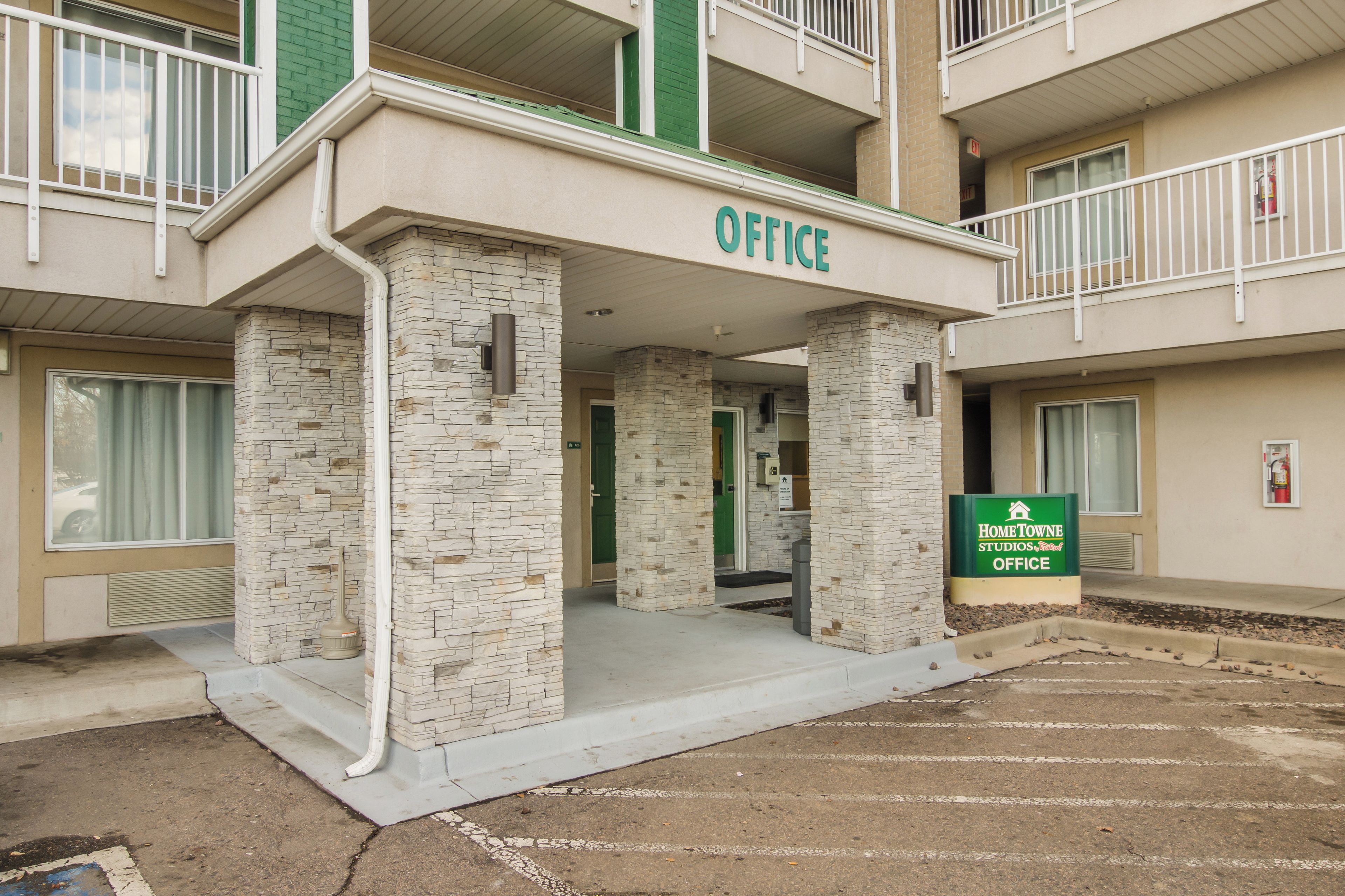 A building with an 'OFFICE' sign, a 'HomeTOWNE Studios Office' sign, and a fire extinguisher on the wall.