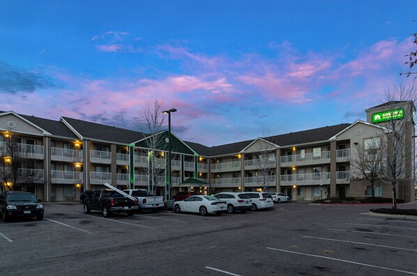 A motel with multiple floors, a parking lot, and a sign indicating the name of the motel. - HomeTowne Studios By Red Roof Denver - Airport/ Aurora (Aurora)