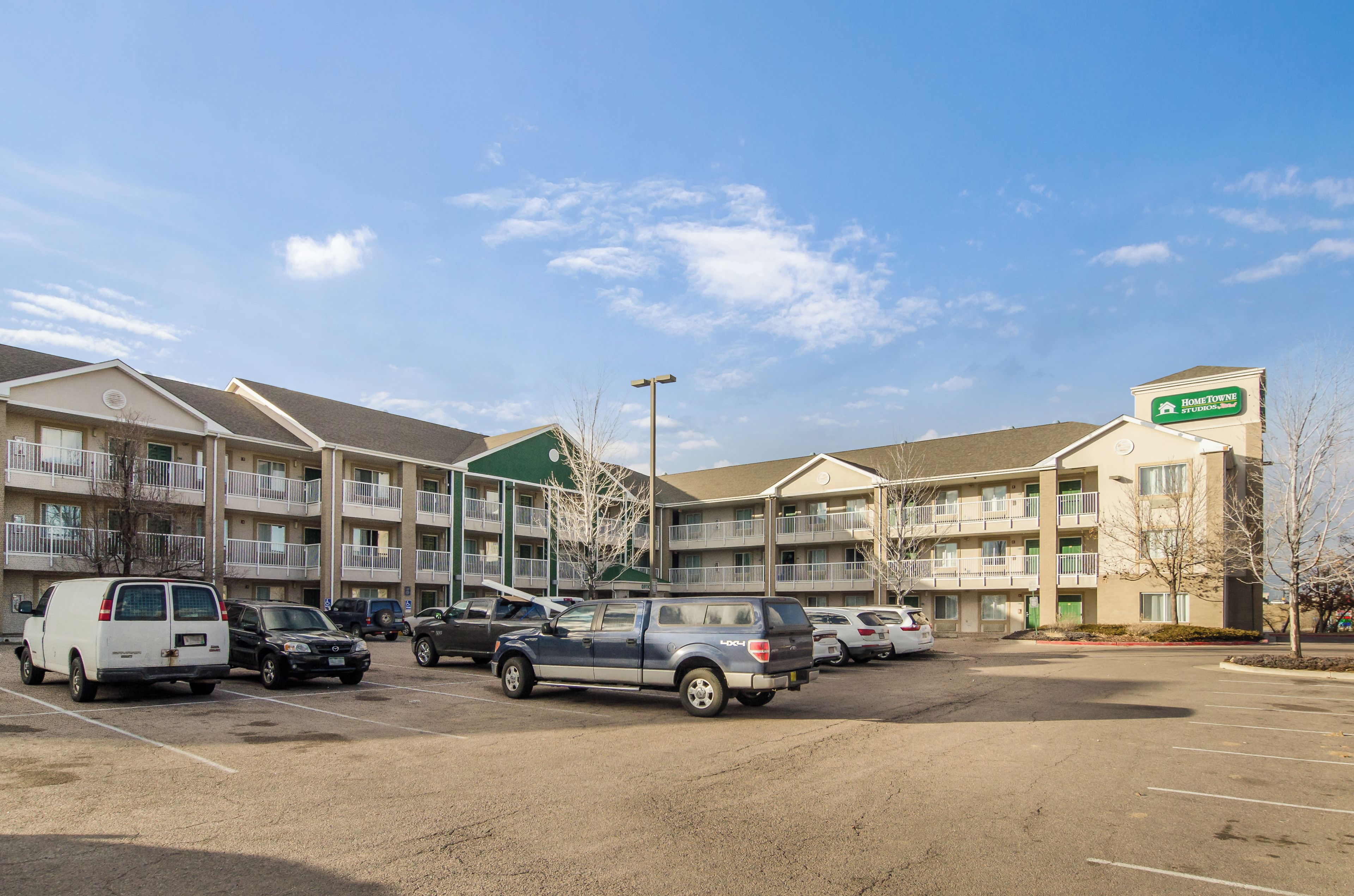 A multi-story motel with a parking lot, featuring a sign for HomeTowne Studios.
