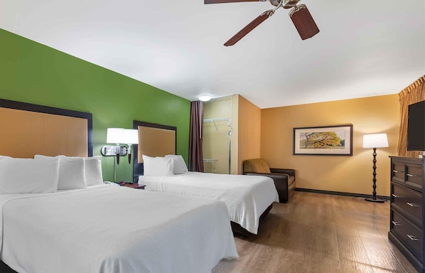 A hotel room with two beds, a ceiling fan, a painting on the wall, and a dresser.