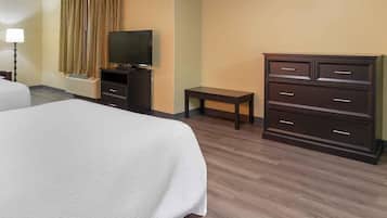 A hotel room with a bed, a television, a dresser, and a small table.
