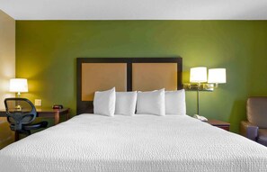 A hotel room with a large bed, two bedside lamps, a desk, a chair, and a telephone. - Extended Stay America Suites Colorado Springs West (Colorado Springs)