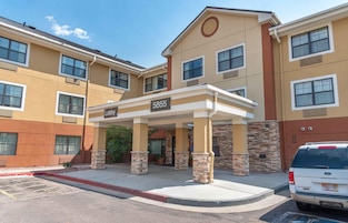 A multi-story hotel with a covered entrance labeled 'Lobby 5855,' featuring a stone and brick facade, multiple windows, and a parking area with a white van.