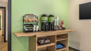 Un espace dédié au café, comprenant une machine à café, des tasses et un panneau d’information.