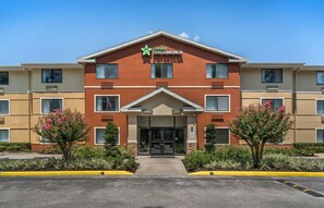 A multi-story hotel with a red facade, a lobby entrance, and a sign indicating 'EXTENDED STAY AMERICA.' - Extended Stay America Suites Daytona Beach Speedway (Daytona Beach)