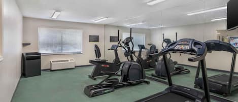 A fitness center with treadmills, elliptical machines, and a mirrored wall.