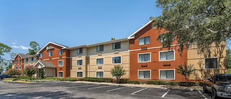 A multi-story hotel with a parking lot and a tree-lined street.