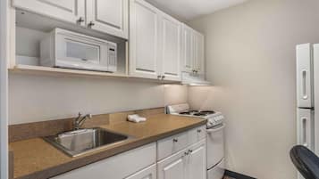 A kitchen with white cabinets, a microwave, a stove, and a sink.