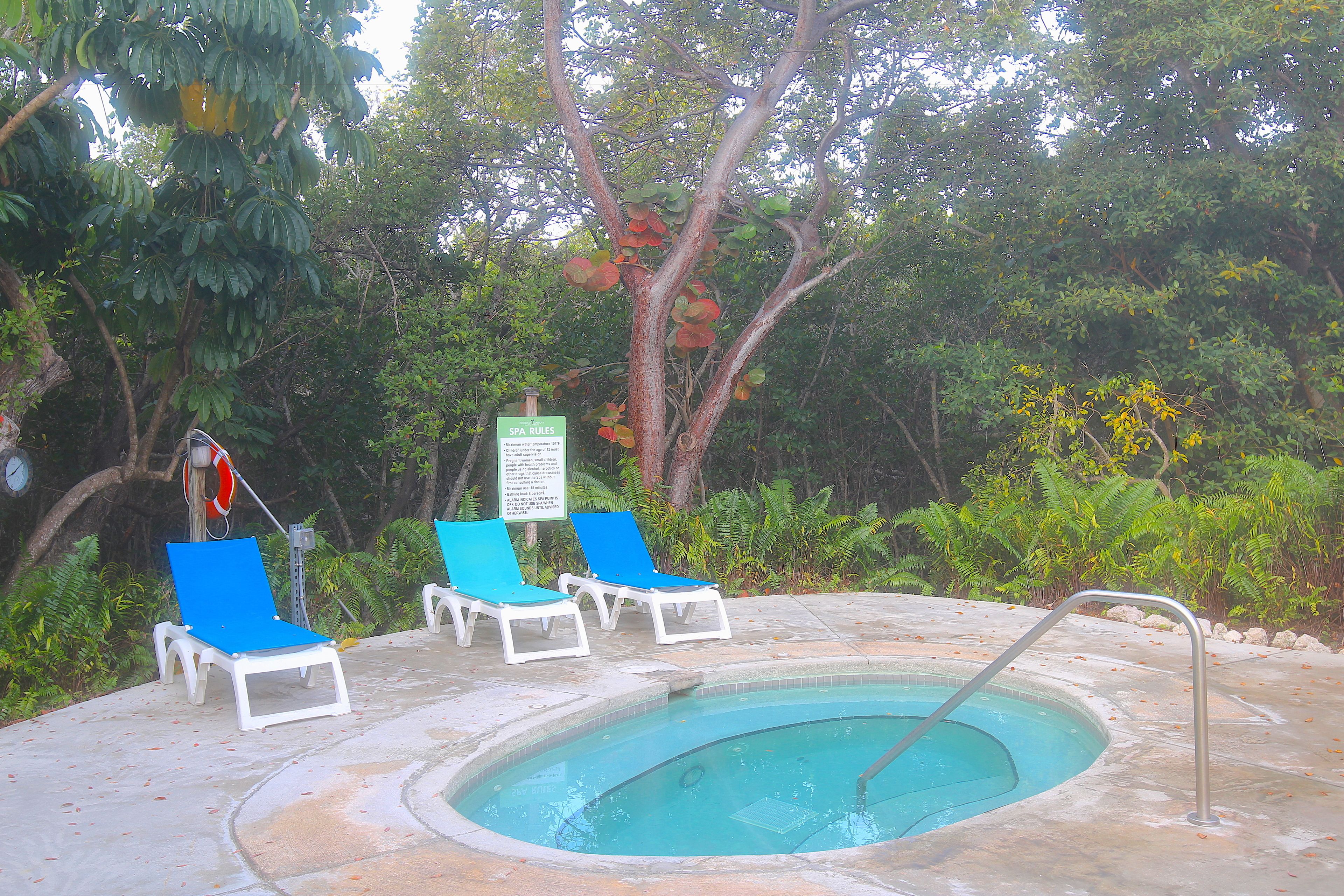 A pool area with lounge chairs and a sign.