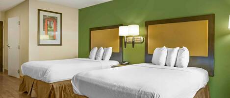 A hotel room with two beds, green walls, and a framed picture on the wall.