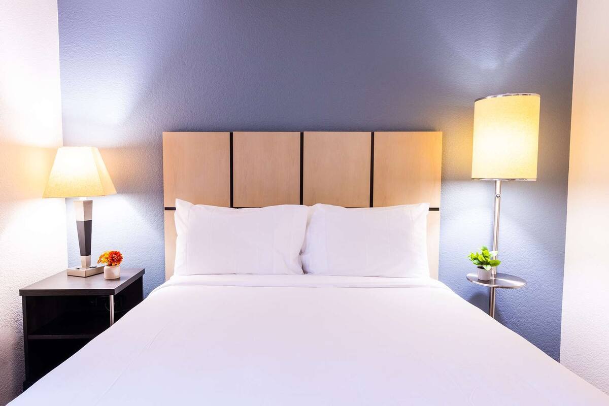 A hotel room with a bed, two bedside tables, and two lamps.