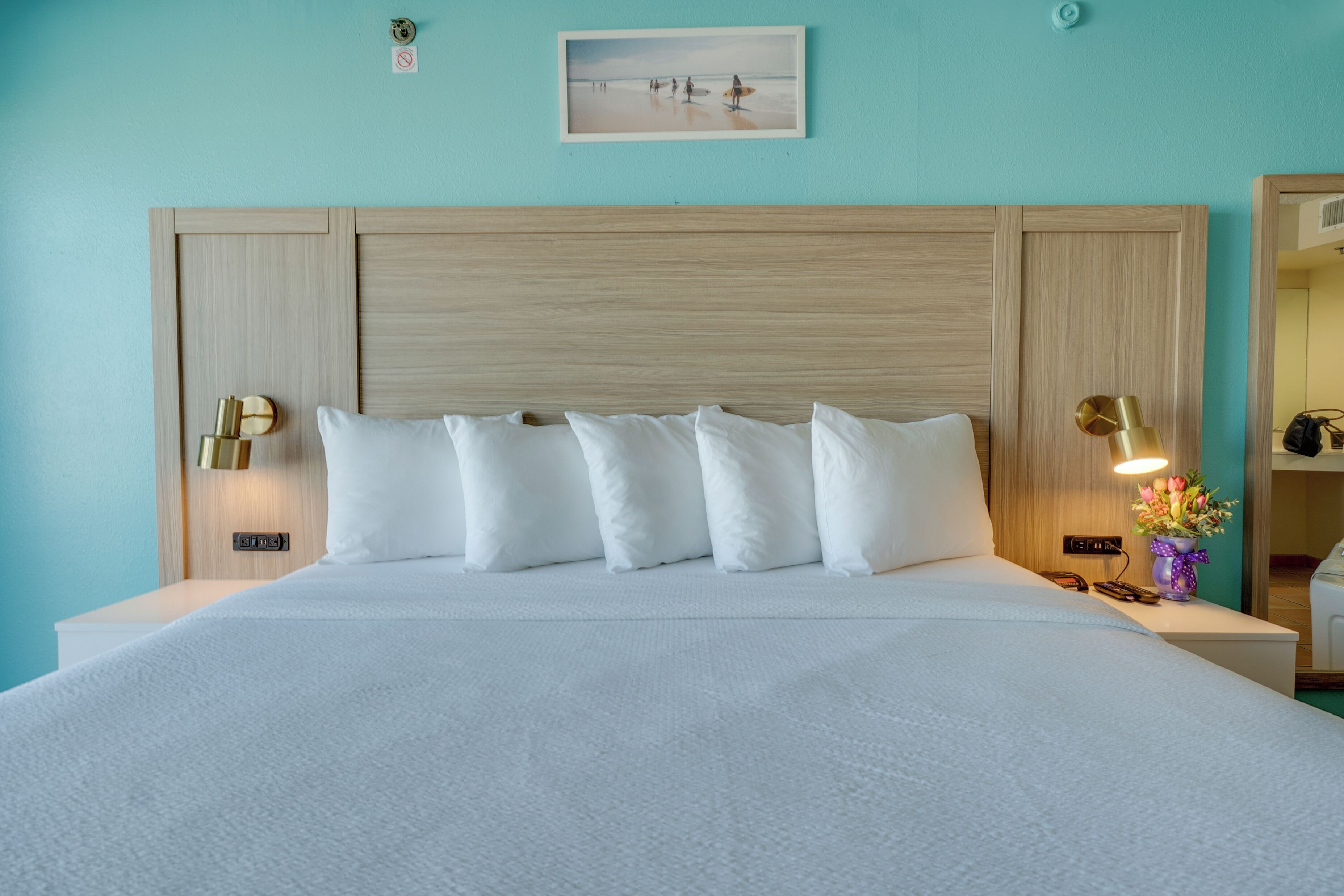 A neatly made bed with white linens and a wooden headboard.