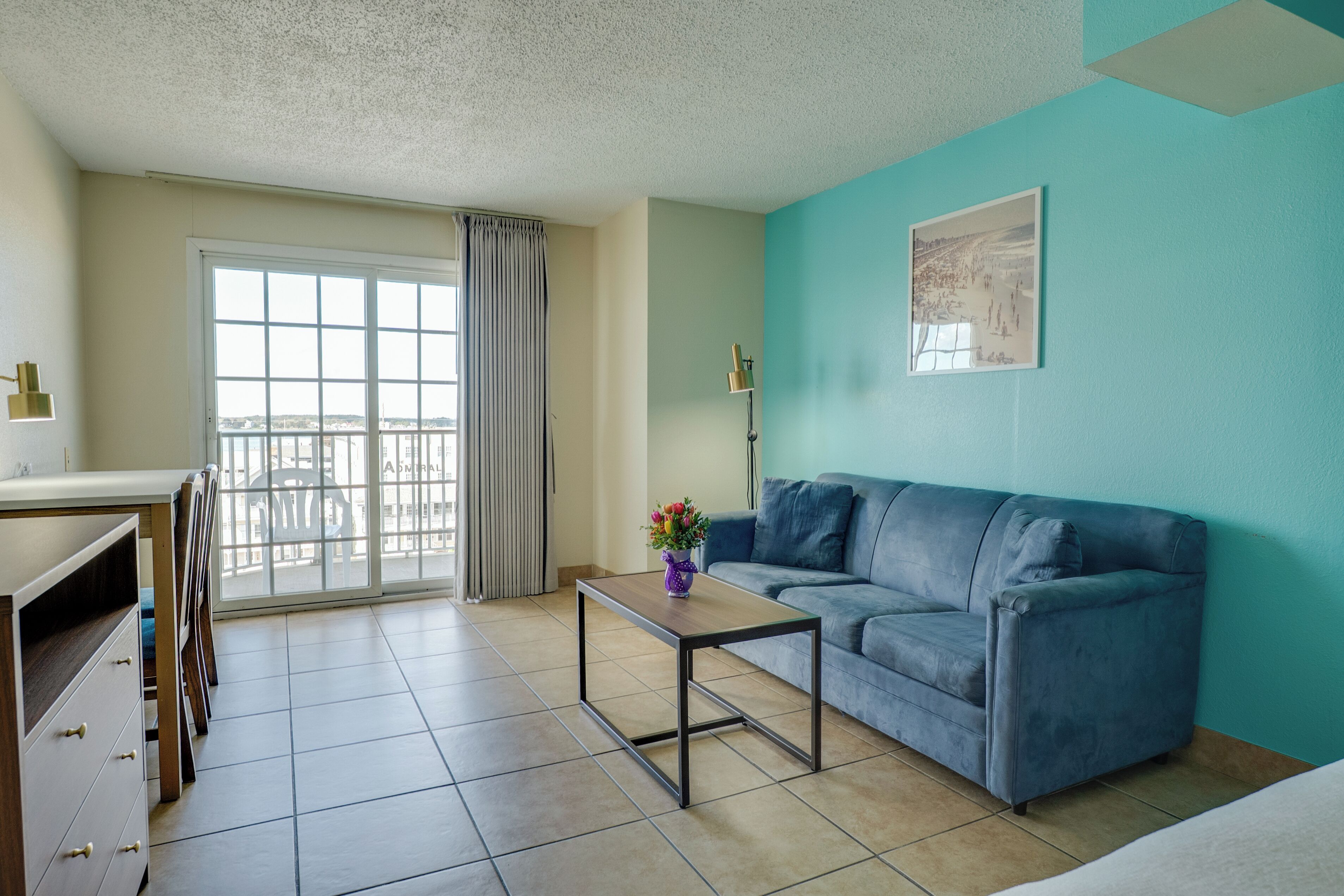 Ein Wohnzimmer mit einer Couch, einem Couchtisch und Blick ins Freie durch ein großes Fenster.