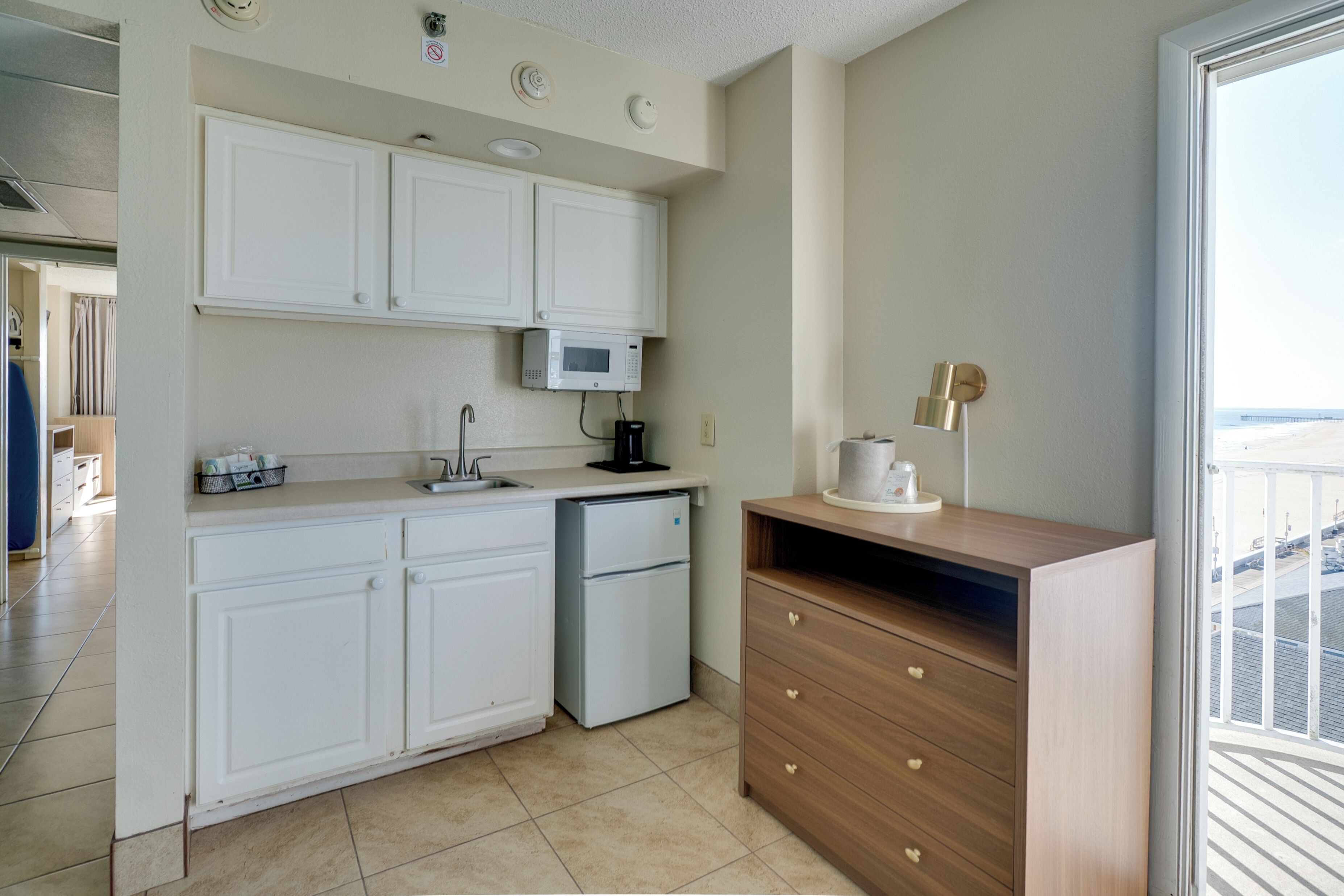 Una cocina compacta con armarios blancos, un microondas y un refrigerador.