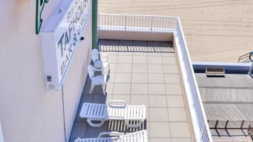 Una terraza frente al mar con sillas reclinables blancas y un letrero que dice 'Paradise Tropical Bar & Grill'.