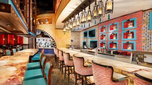 Un restaurant doté d’un long comptoir, de plusieurs espaces de restauration et d’un mur décoratif orné de carreaux à motifs.
