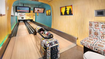 A bowling alley with wooden walls, a bowling lane, pins, and a bowling ball rack.