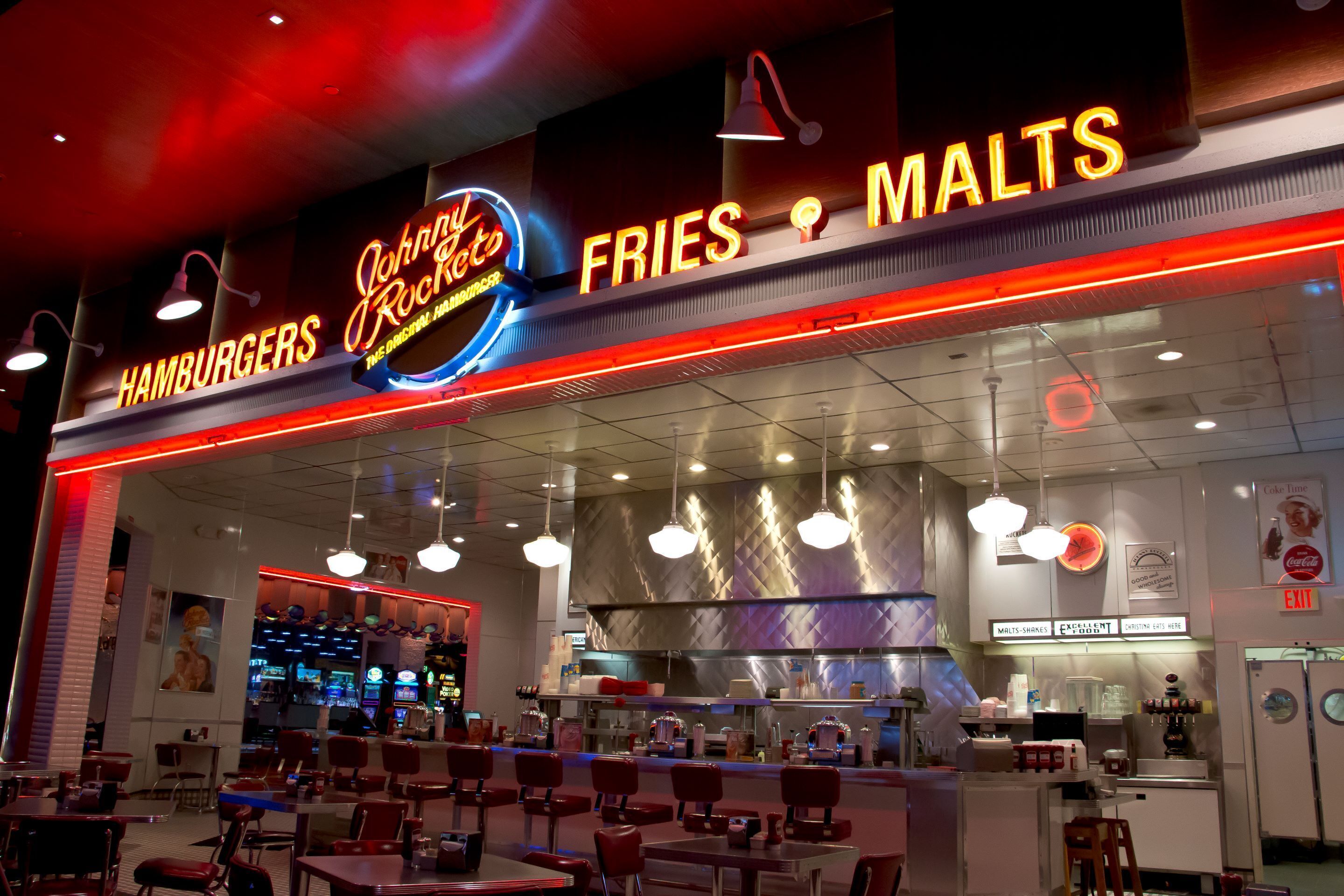 Ein Restaurant mit Neonreklamen für 'John's Rocker' und 'Malts Fries'.
