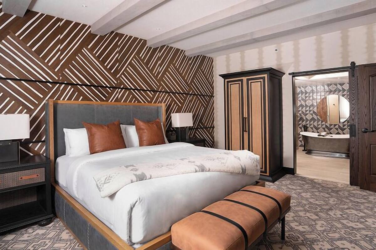 Een moderne hotelkamer met een groot bed, een nachtkastje, een bankje en een kledingkast.