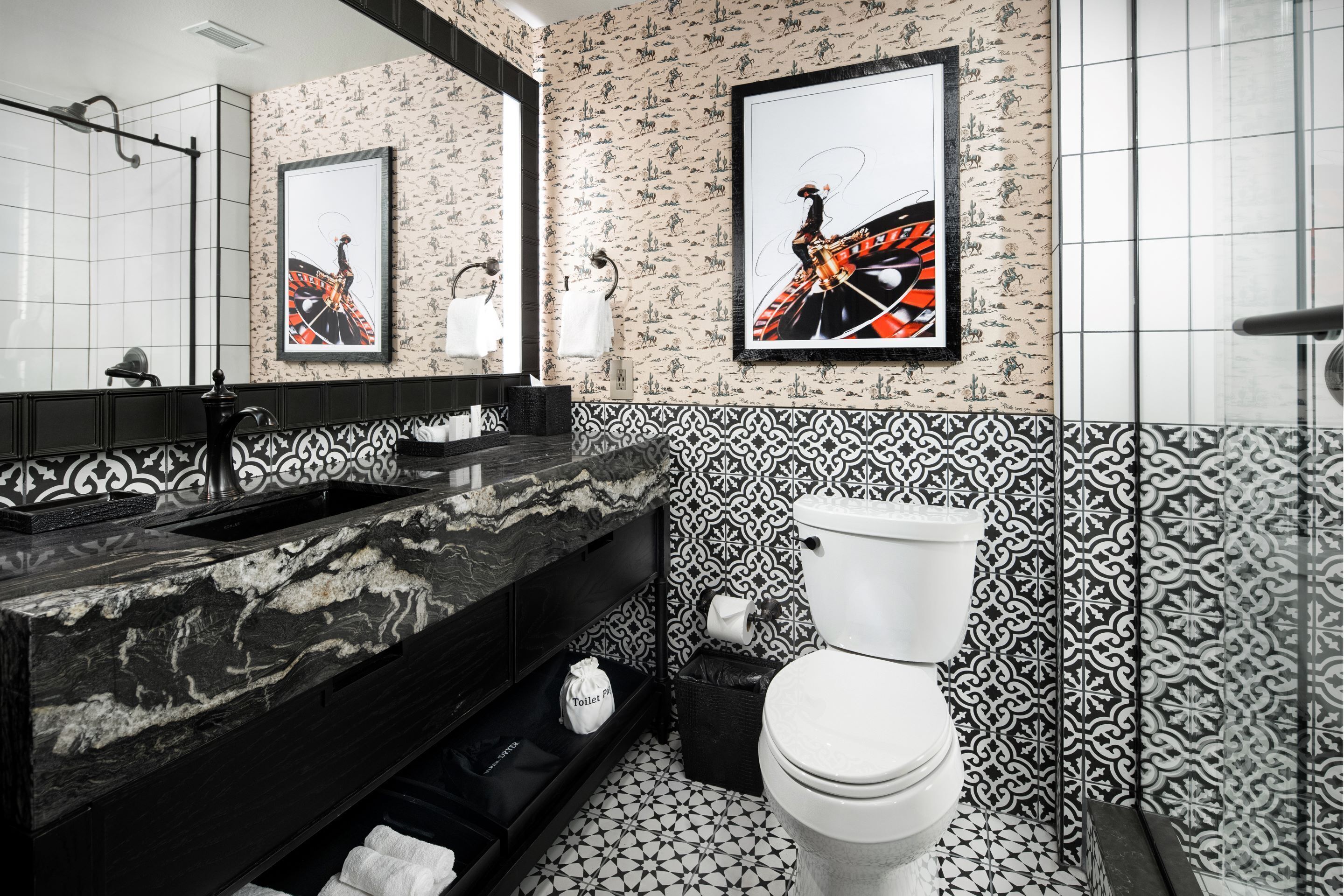 Ein modernes Badezimmer mit einem schwarzen Marmorwaschbecken, einer Toilette und einem Musterfliesenbelag.