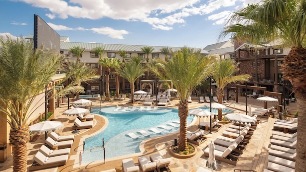 Un espace piscine avec des chaises longues et des palmiers.