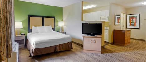 Een hotelkamer met een bed, televisie, bureau en kast.