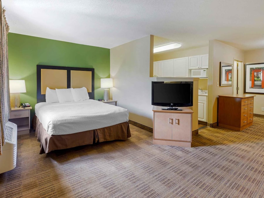 Een hotelkamer met een bed, televisie, bureau en kast.