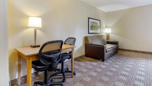 A hotel room with a desk, office chair, sofa, and two bedside lamps. - Extended Stay America Select Suites Raleigh RTP 4610 Miami B (Durham)