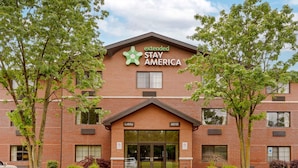 A Stay America hotel with a brick facade, a green logo, and a lobby entrance. - Extended Stay America Select Suites Raleigh RTP 4610 Miami B (Durham)
