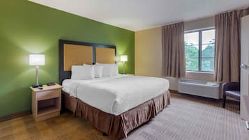 Een hotelkamer met een bed, nachtkastjes, een raam met gordijnen en een radiator.