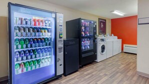 A room with vending machines, a trash bin, and a laundry area. - Extended Stay America Select Suites Raleigh RTP 4610 Miami B (Durham)