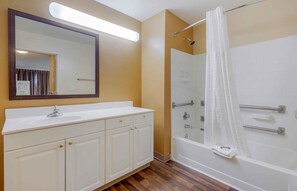 A bathroom with a white vanity, a large mirror, a shower with a glass door, and a white bathtub.